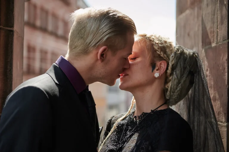 Ein Hochzeitsfoto von einem Paar dass sich im Gegenlicht der Sonne küsst.