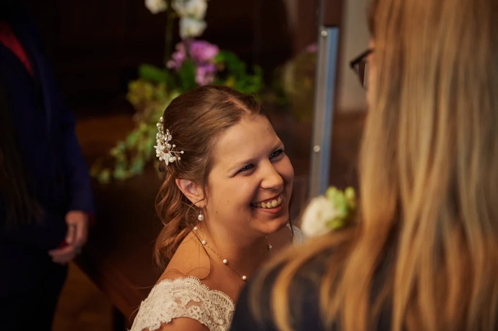 Die Braut schaut ihrem Bräutigam in die Augen während sie vor der Standesbeamtin stehen.